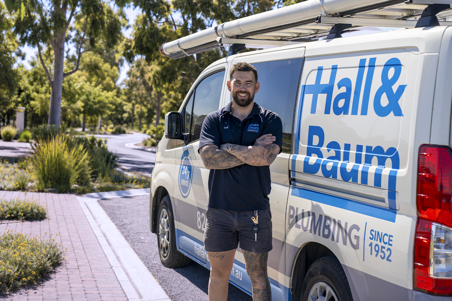 A Hall & Baum plumber smiling in front of a Since 1952 branded van