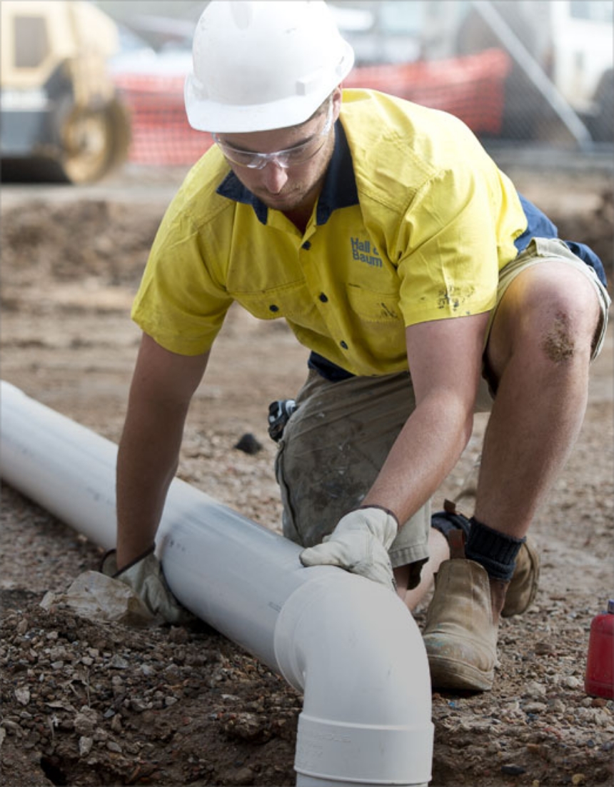A Hall & Baum tradesperson fitting stormwater pipe on a worksite