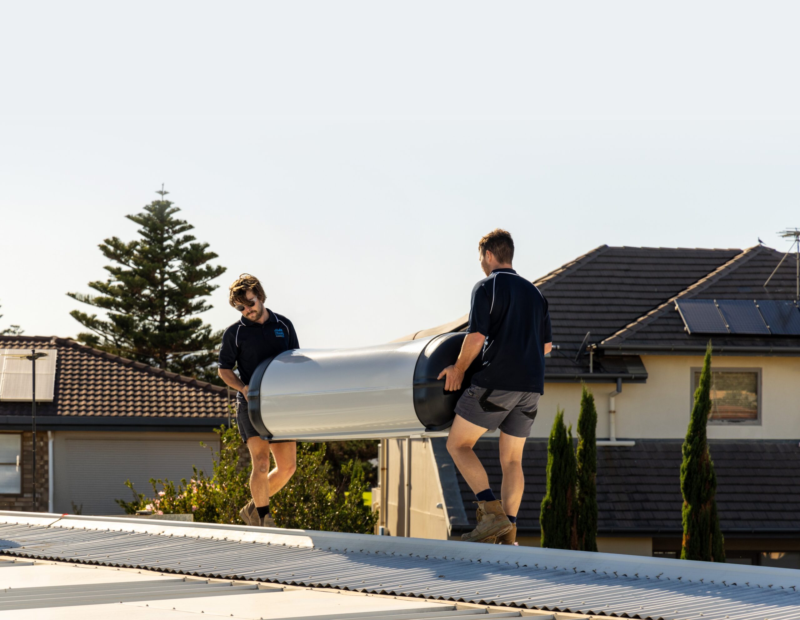 Hall & Baum tradespeople installing a hot water system on a rooftop