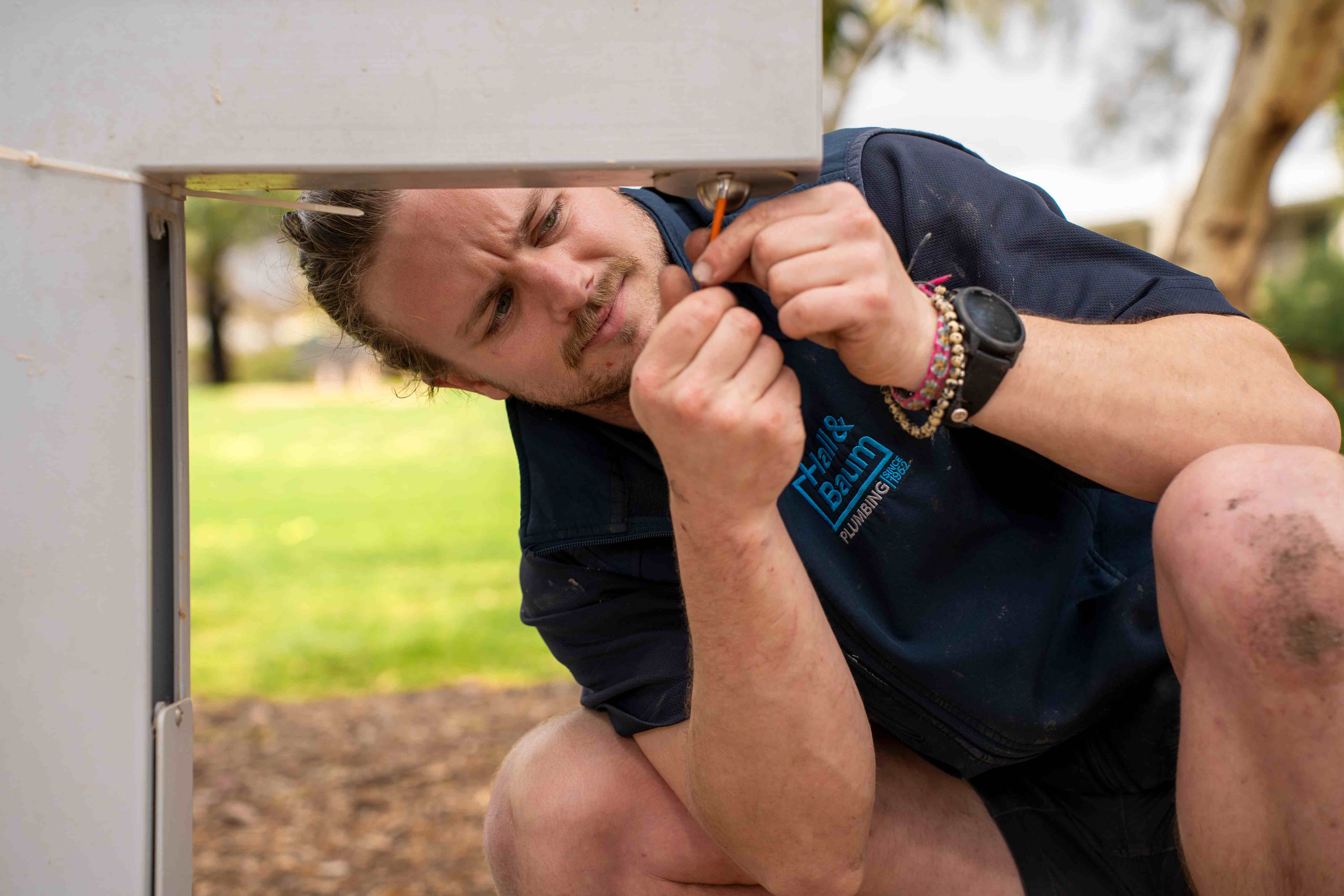 A Hall & Baum plumber concentrating on a repair