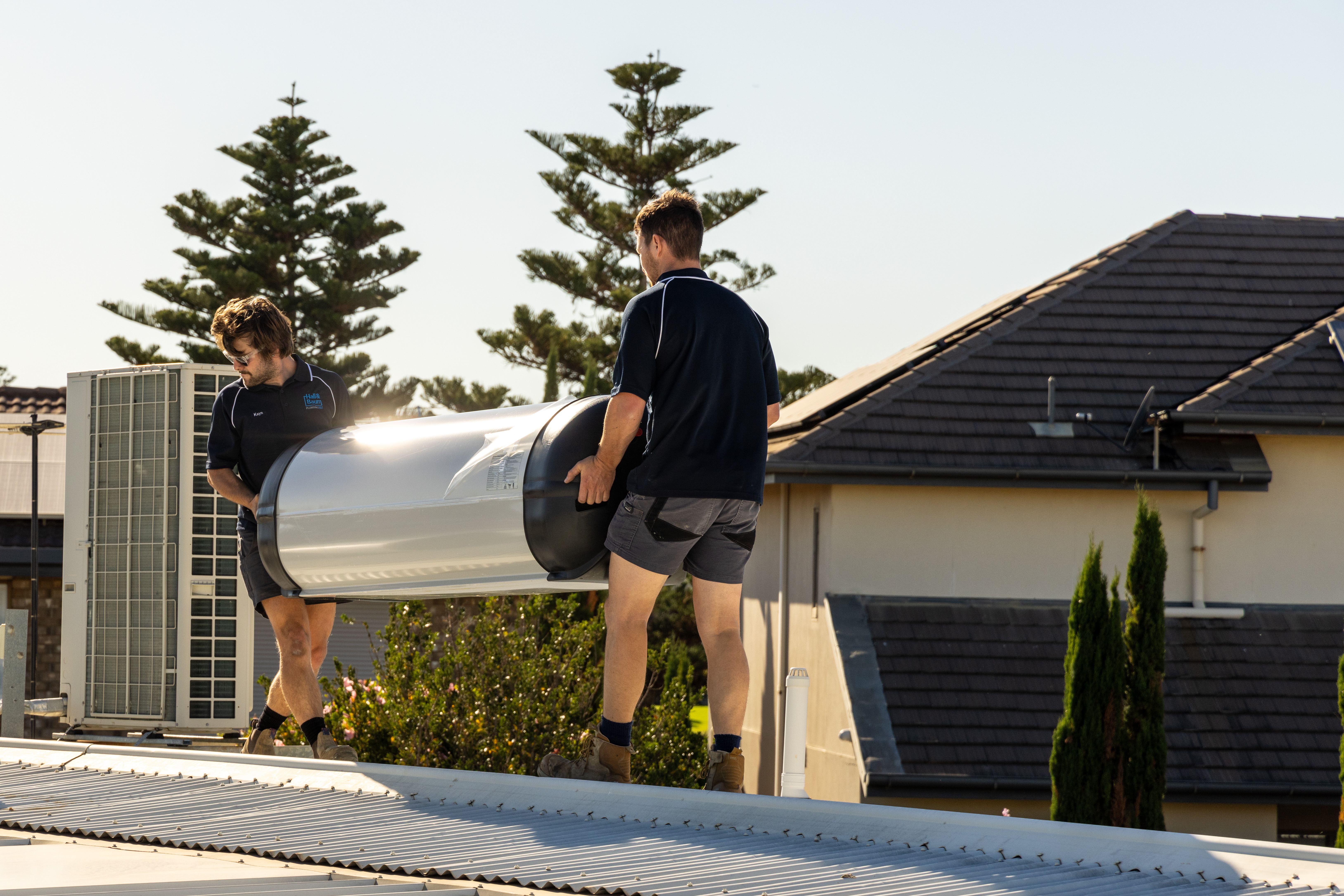 Hall & Baum tradespeople installing a hot water cylinder on an Adelaide rooftop