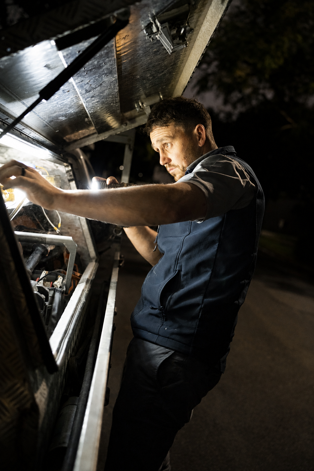A technician working on a service van after hours